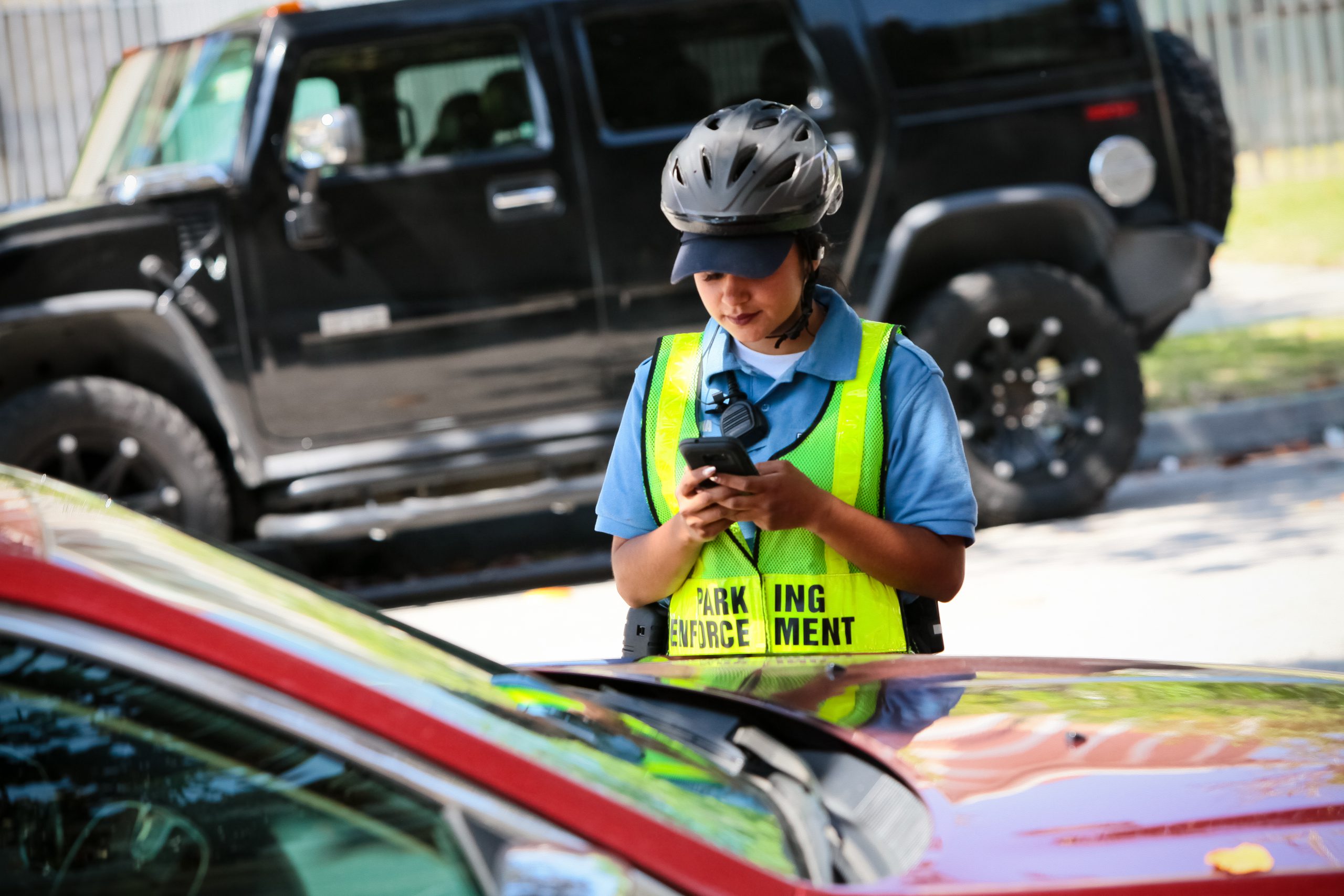 Parking enforcement services - officer looking at phone in front of car